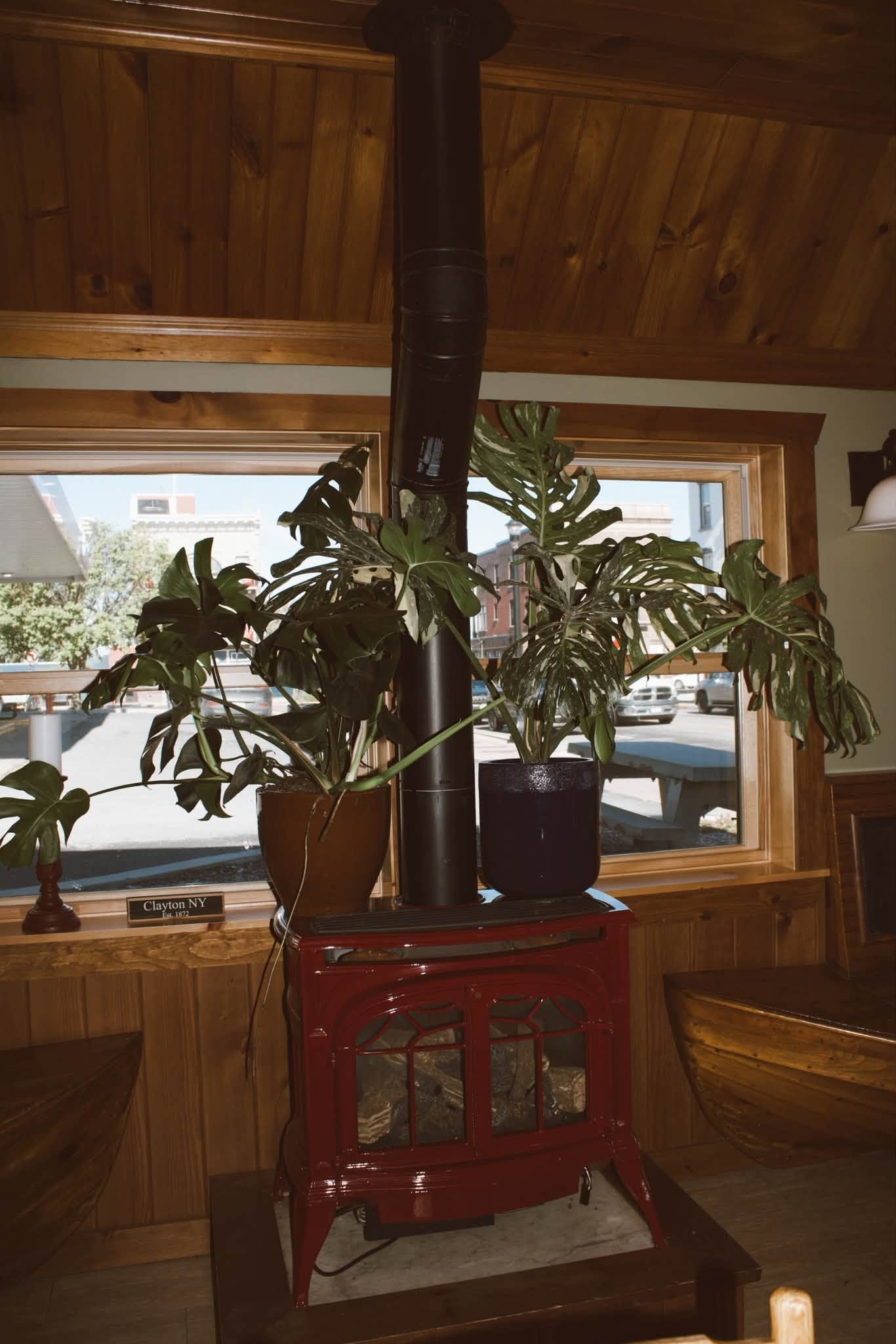 Cozy red wood stove and monstera plants inside The Kove